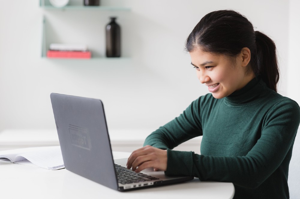 Young woman smiling as she works at her laptop